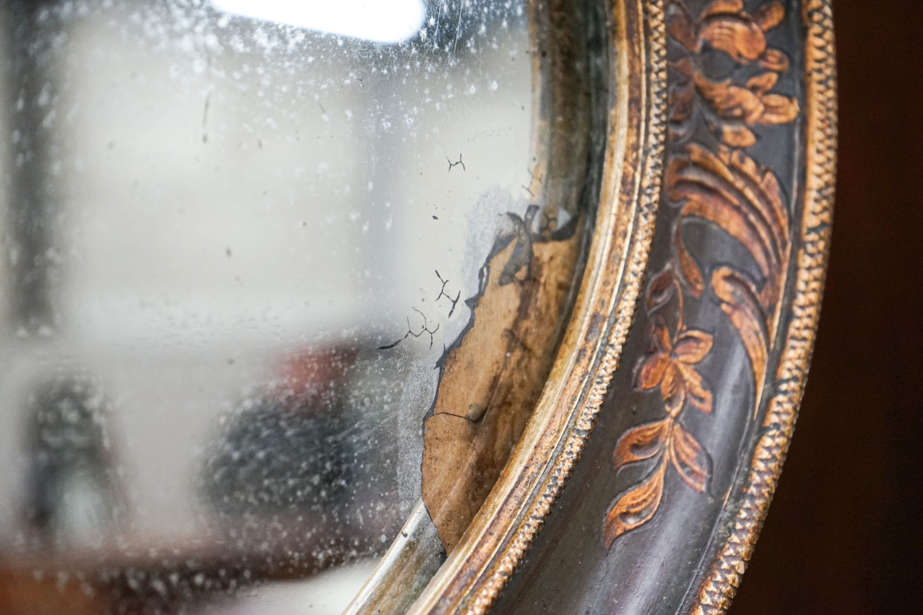 An oval painted parcel gilt bevelled wall mirror, width 84cm, height 51cm